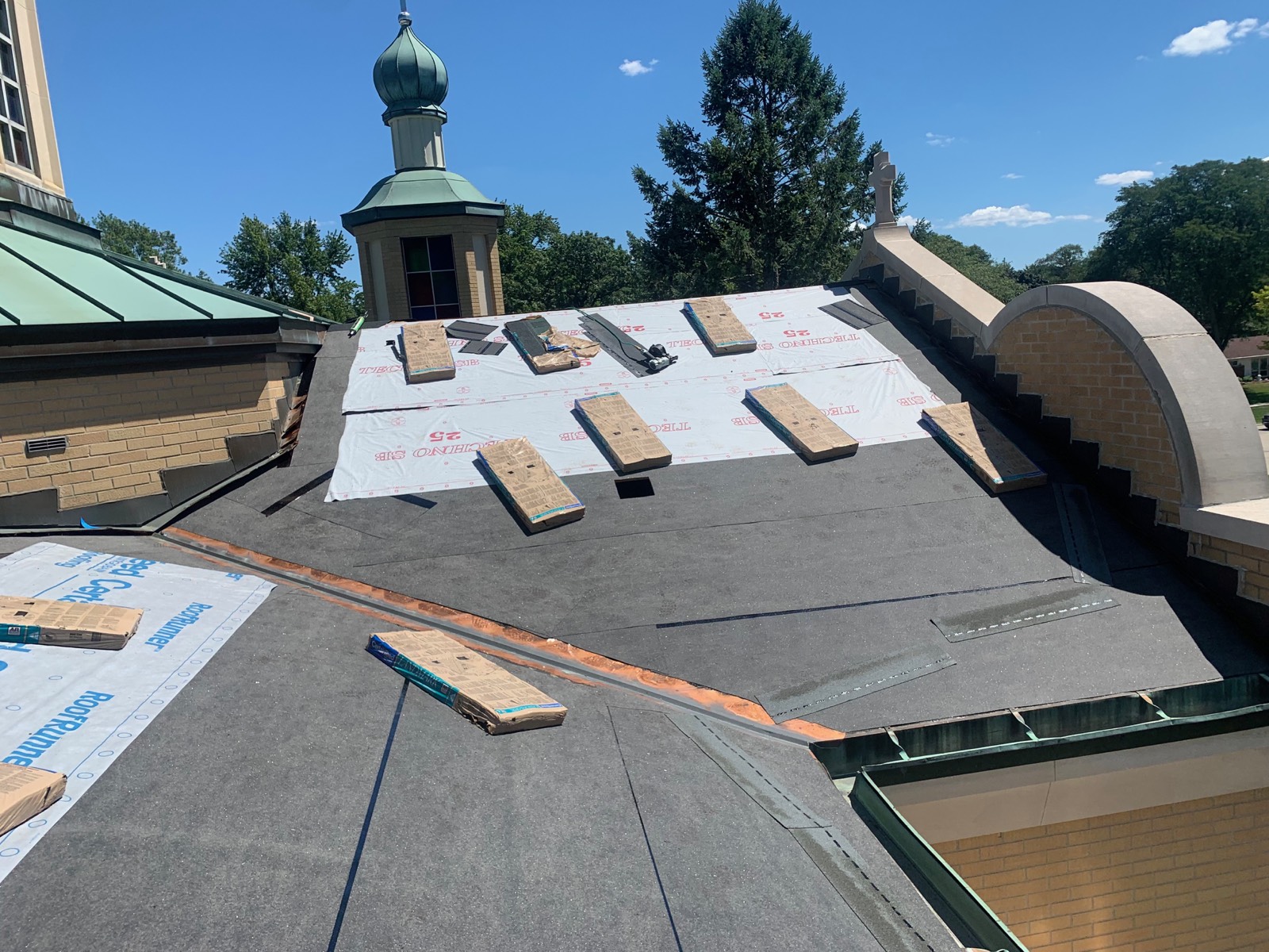Church roof with ice and water shield installed and bundles staged below the cupola