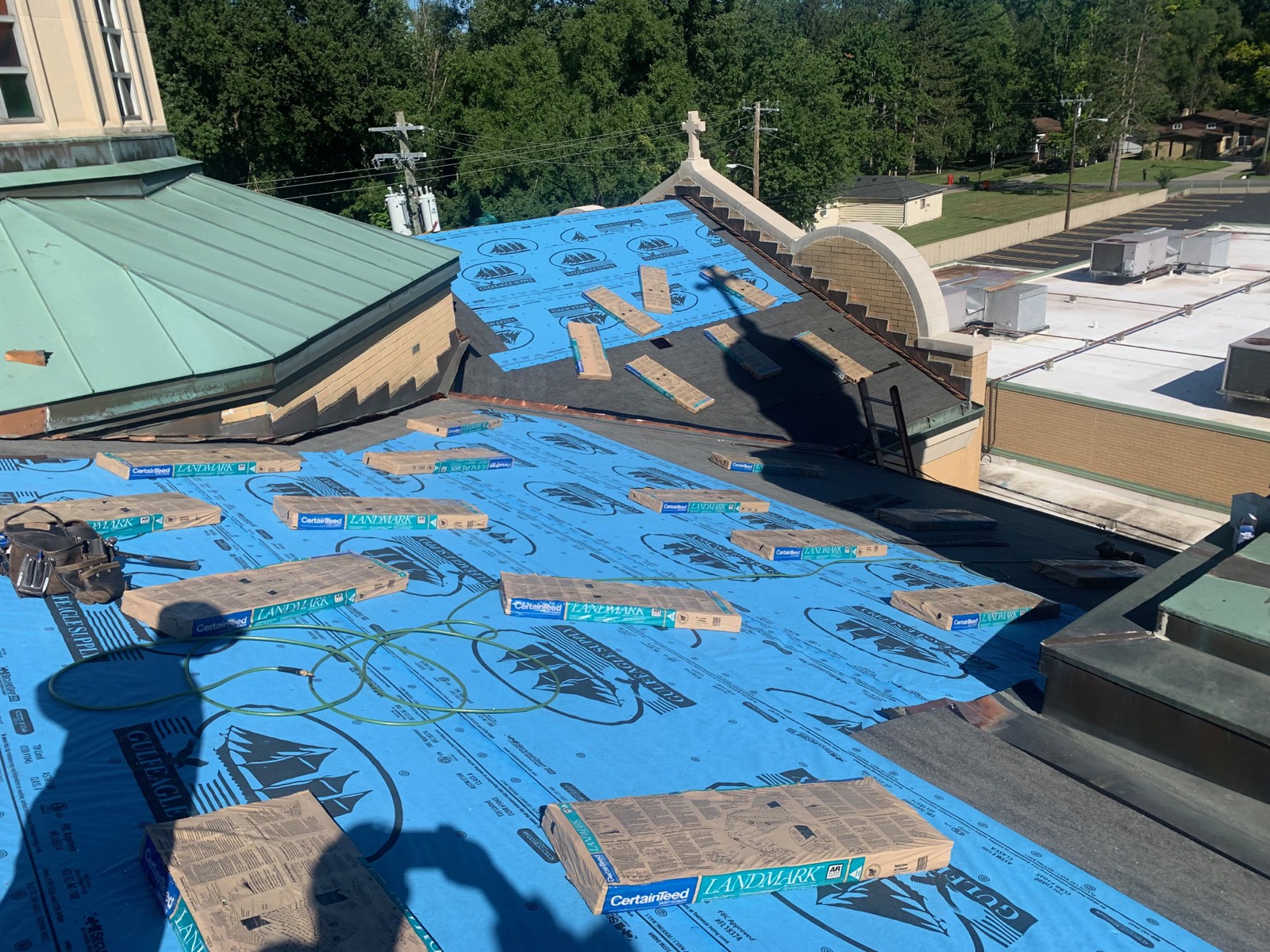 Commercial church roof covered in synthetic underlayment with shingle bundles staged