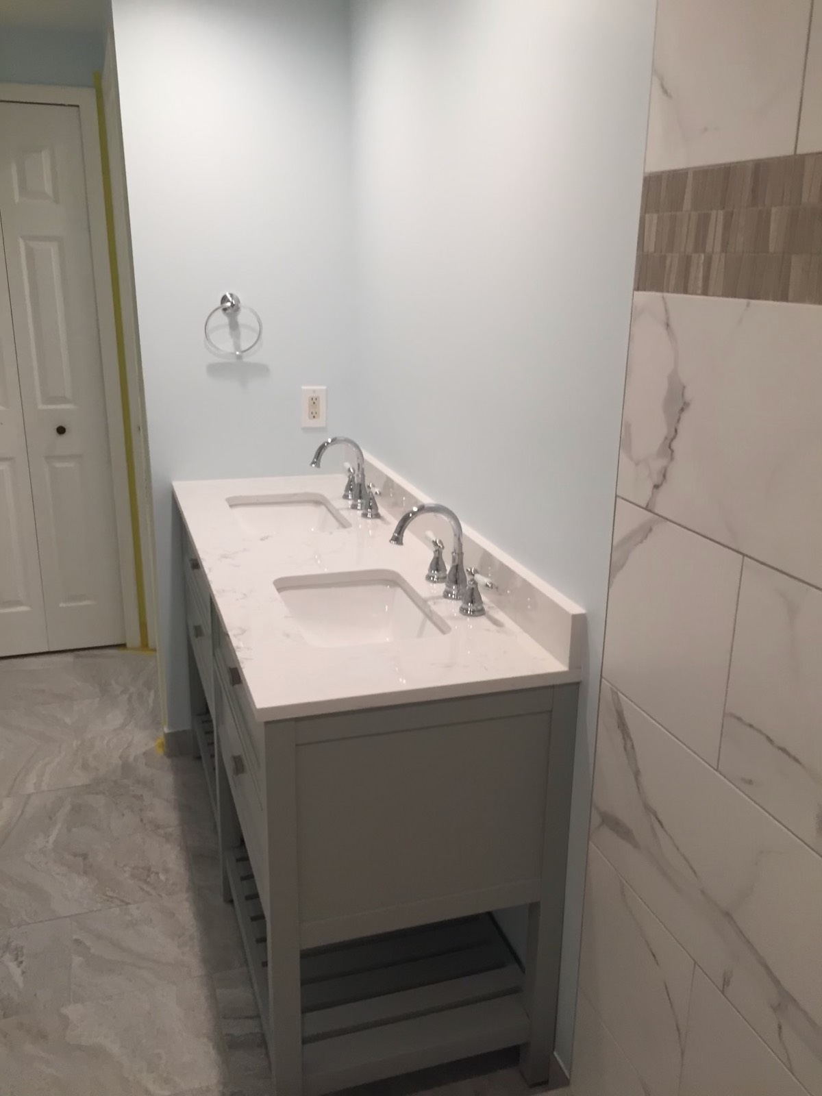 Double vanity with a white quartz top and undermount sinks beside a marble-look tile shower wall