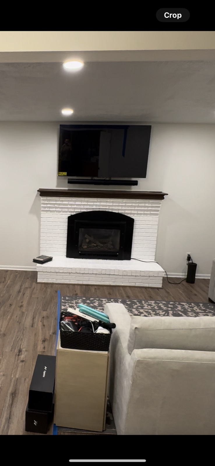 The fireplace finished with painted white brick under the dark mantel and a mounted TV