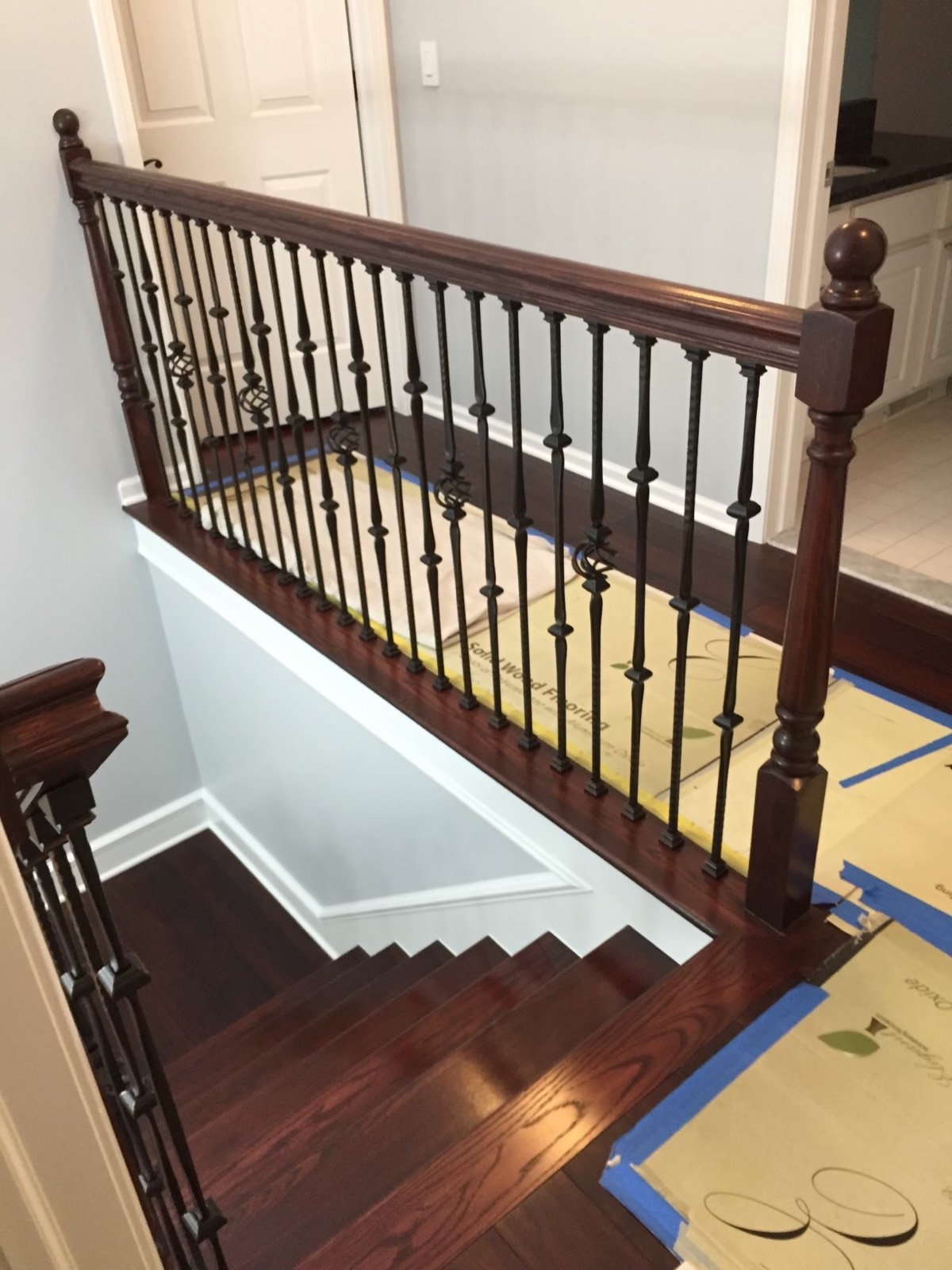 Landing railing with a stained oak handrail, newel post and wrought-iron balusters