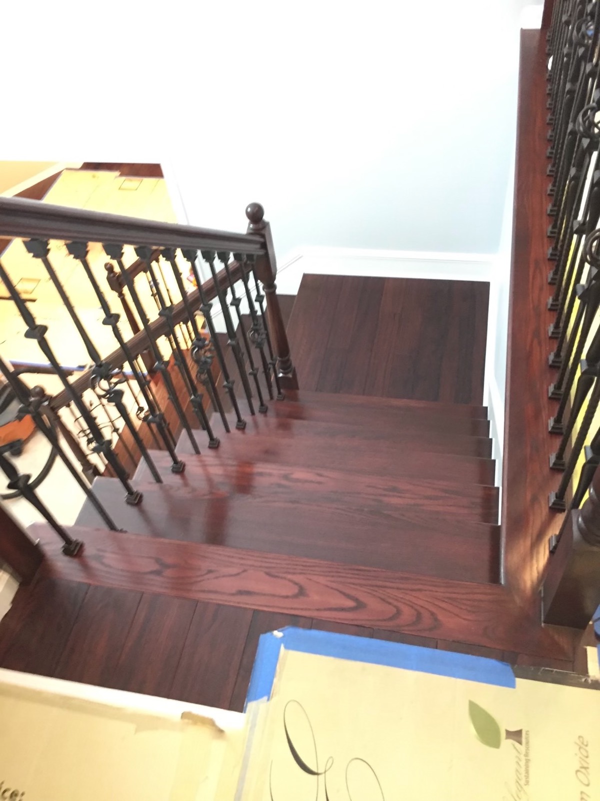 Looking down a staircase with new dark-stained oak treads and iron balusters