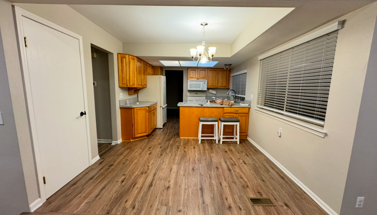 The same kitchen finished with a new drywall ceiling and skylight, chandelier and wide-plank vinyl flooring