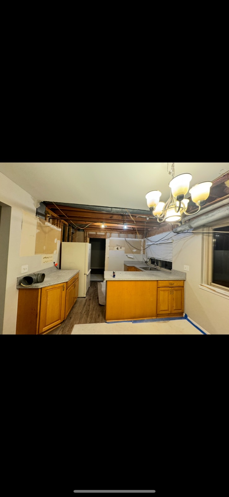 Kitchen during demolition with the ceiling opened to the joists above the existing oak cabinets